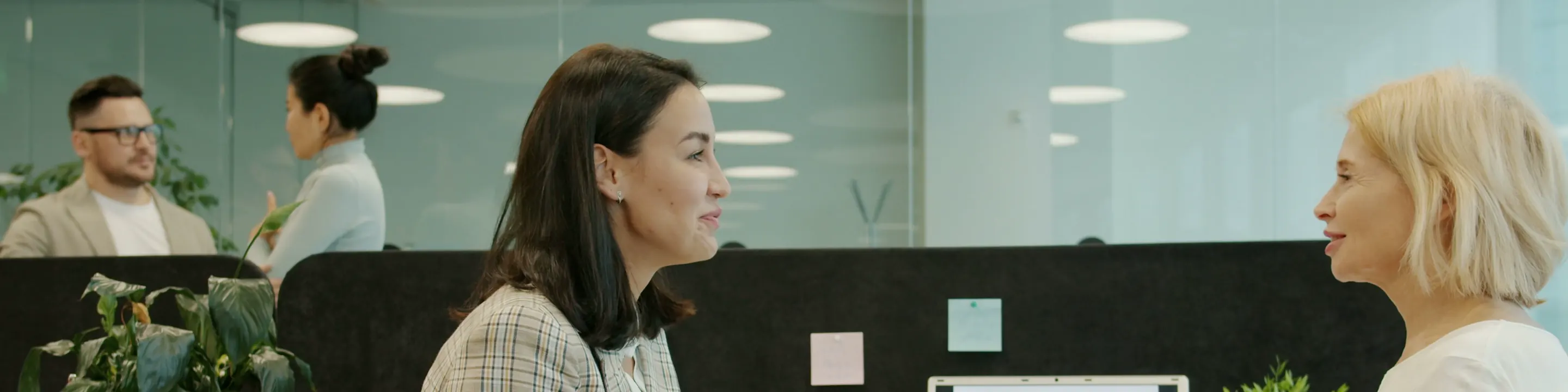 Two colleagues talking across their desks in an open office