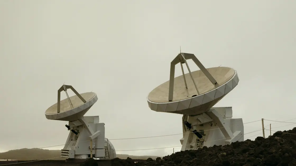Two large antenna dishes on a mountain ridge